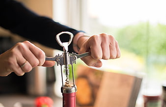 Hands Using Corkscrew to Open Red Wine Bottle