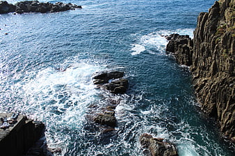 High angle view of crashing waves against rocky coastal cliffs
