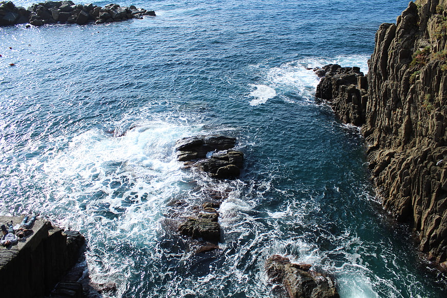 High angle view of crashing waves against rocky coastal cliffs