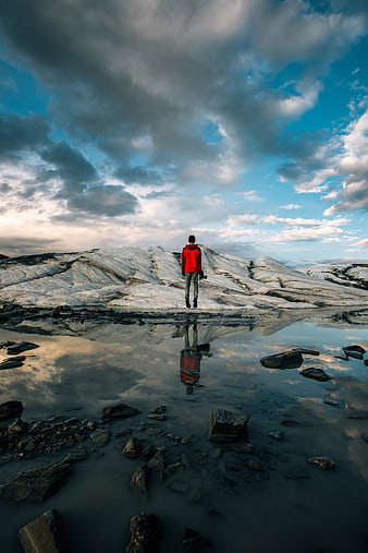Man in Red Jacket Standing on Glacial Ice with Reflection