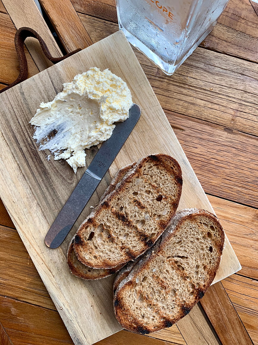 Toasted rustic bread with whipped butter on wooden board