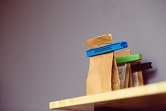 Brown paper tea bags with colorful clips on wooden shelf