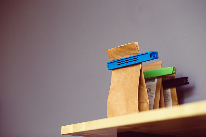 Brown paper tea bags with colorful clips on wooden shelf