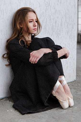 Melancholic Young Woman in Ballet Shoes Sitting Against Wall