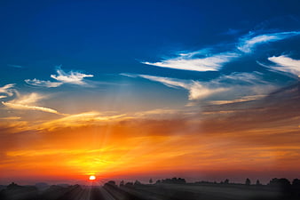 Vibrant sunset with sunbeams over rural landscape silhouette