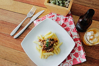 Overhead view of pasta dish with beer on wooden table
