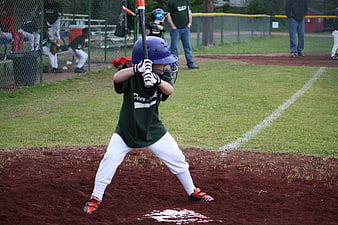 Young boy in green uniform holding baseball bat at home plate