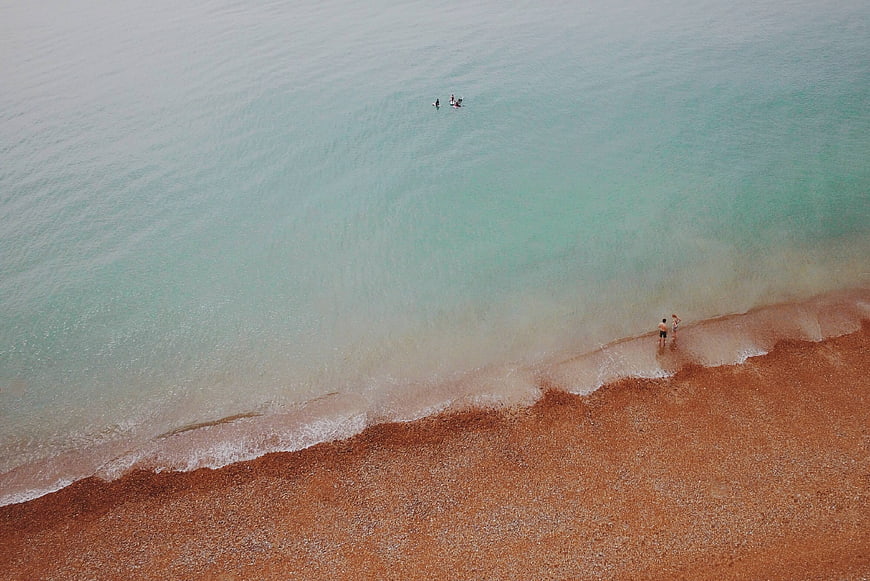 Aerial View of Turquoise Sea and Sandy Beach with People