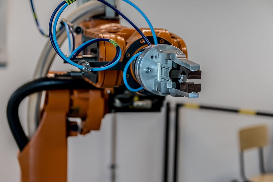 Close-up of orange industrial robotic arm with blue cables