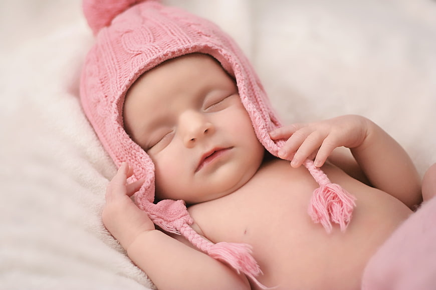 Sleeping newborn baby girl in pink knitted hat