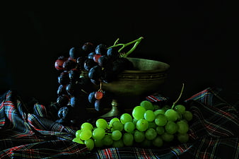 Dark moody still life of green and purple grapes in a bowl