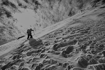 Black and white mountaineer climbing steep snowy mountain slope