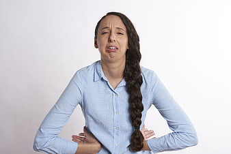 Woman holding back in pain against white background
