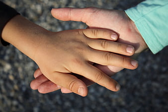 Close-up of adult hand holding child's hand outdoors