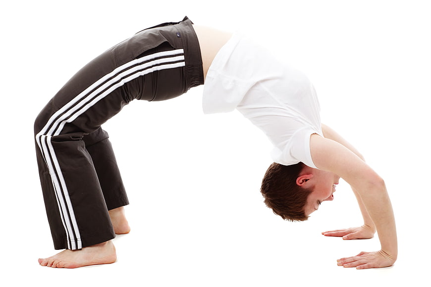Young man performing a backbend flexibility exercise on white background