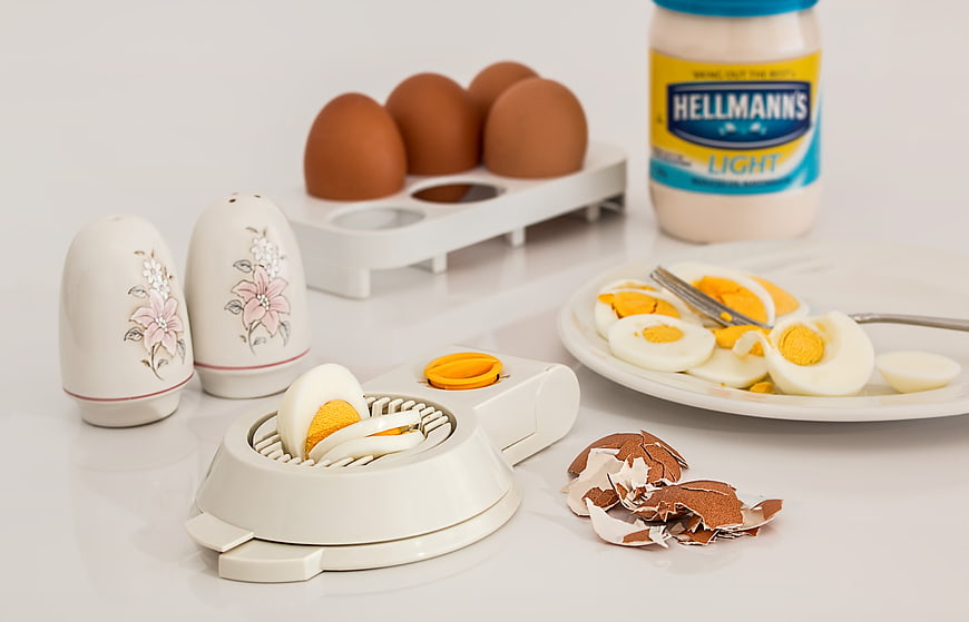 Hard Boiled Eggs With Slicer And Mayonnaise On White Table