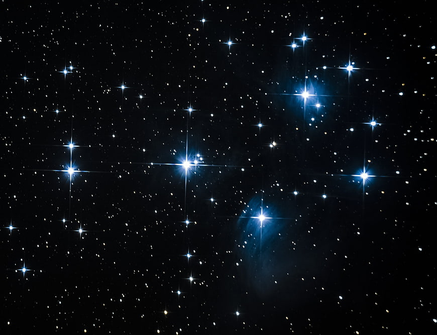 Deep space star field with bright blue stars and faint nebula