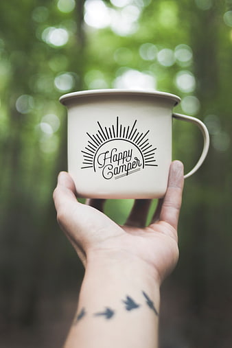 Hand holding Happy Camper mug in forest
