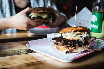 Pulled pork burger on wooden table with person eating
