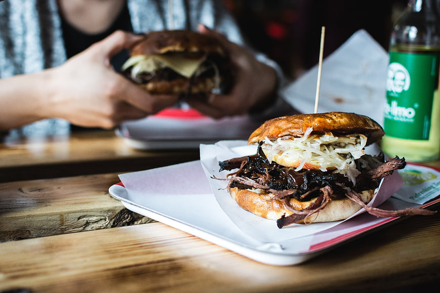 Pulled pork burger on wooden table with person eating