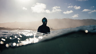 Surfer Silhouette in Ocean Water with Sun Flare