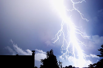 Dramatic Lightning Strike Over Silhouetted Trees And Building