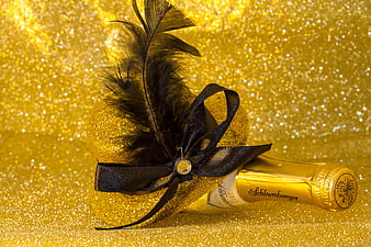 Luxury champagne bottle with black feather on gold glitter background