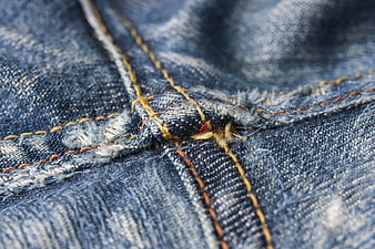 Close-up of blue denim fabric texture with yellow stitching