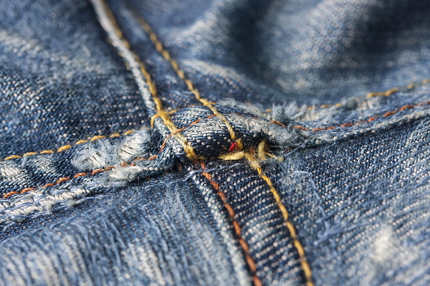 Close-up of blue denim fabric texture with yellow stitching
