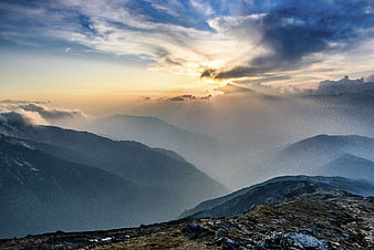 Dramatic mountain landscape with sun rays breaking through clouds
