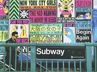 Man walking past colorful graffiti wall at New York City subway entrance