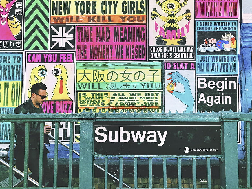 Man walking past colorful graffiti wall at New York City subway entrance