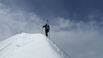 Backcountry skier standing on snowy mountain ridge summit