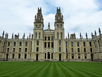 Historic Gothic University College Building With Twin Towers And Green Lawn
