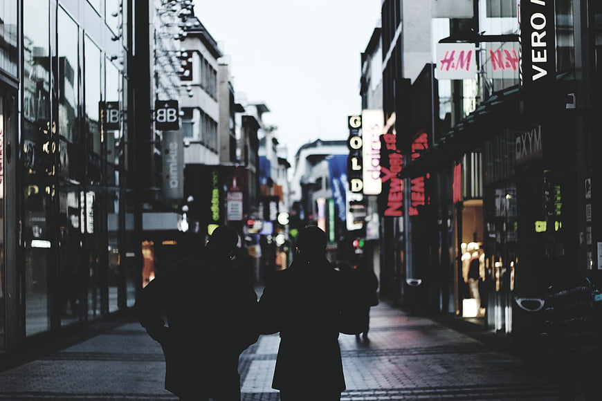 Silhouettes of Couple Walking Down Urban Shopping Street