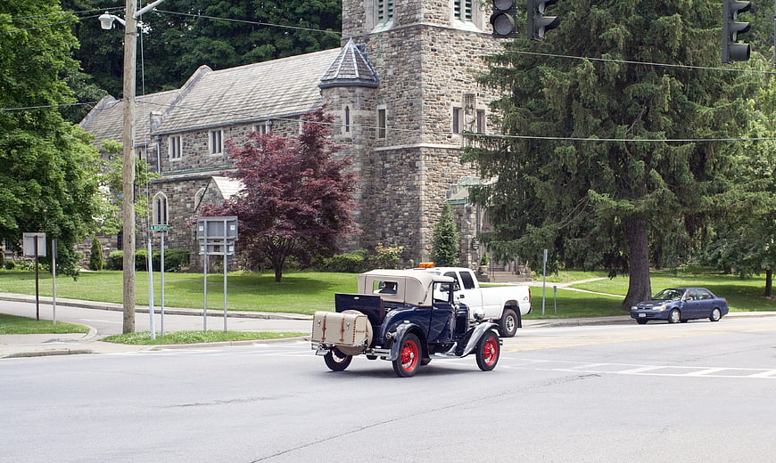 Vintage Ford Model A driving past stone church