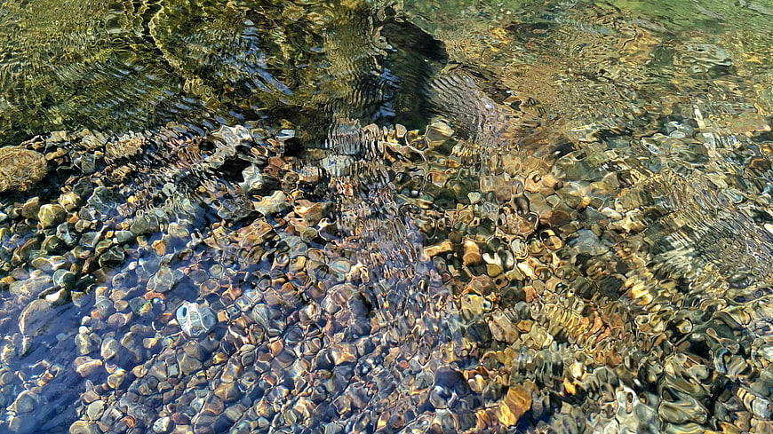 Clear rippling water over smooth river stones