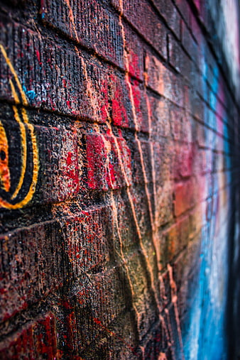 Close-up of colorful graffiti on a textured brick wall