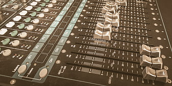 Close-up of professional audio mixing console with sliders and knobs