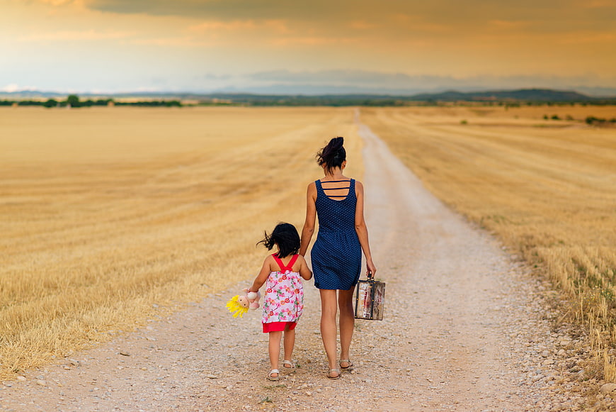 Mother and daughter walking away on rural dirt road