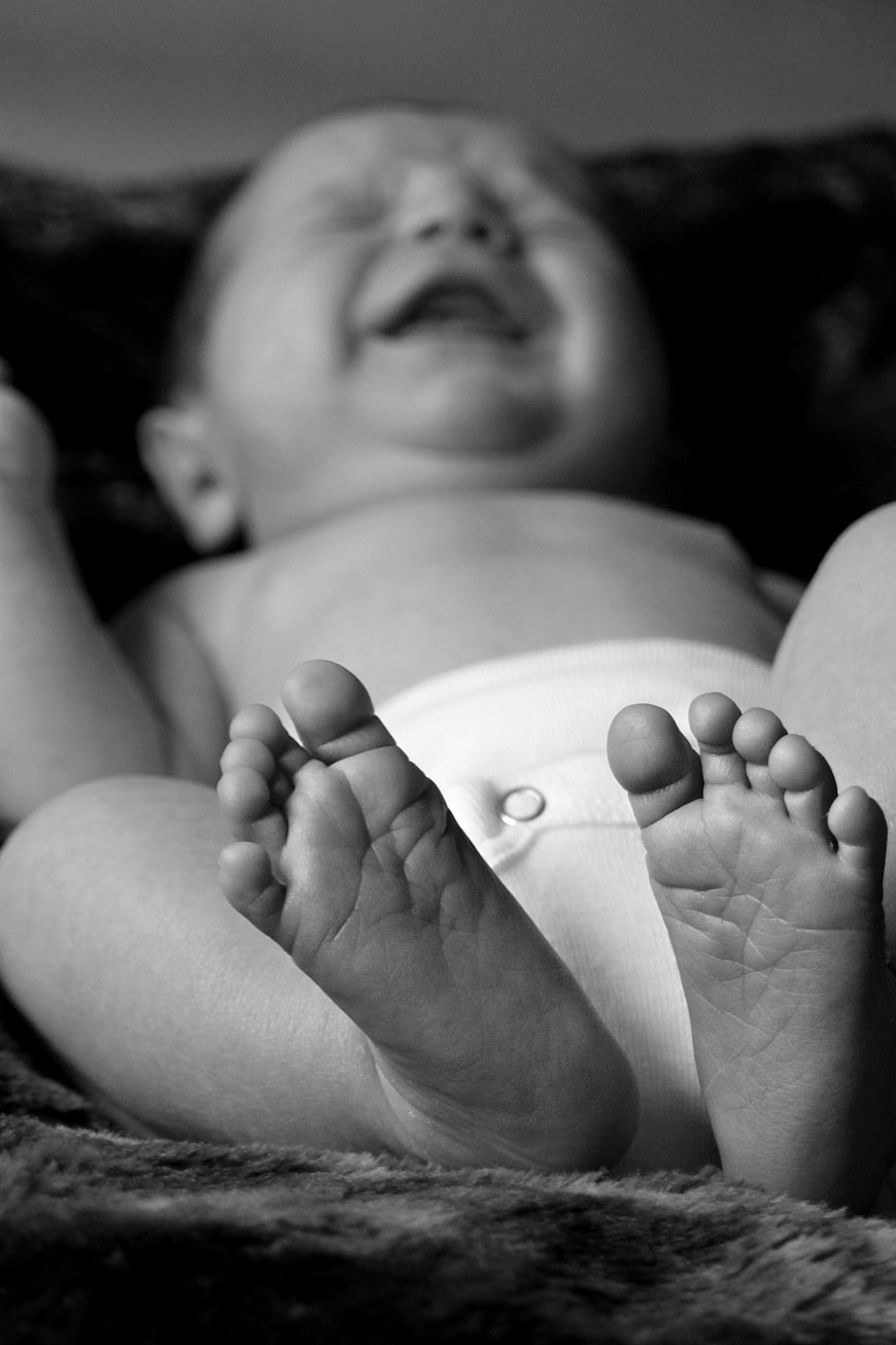 Black and white photo of a crying baby with feet in focus