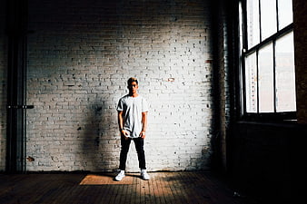 Young man standing in front of white brick wall with window light