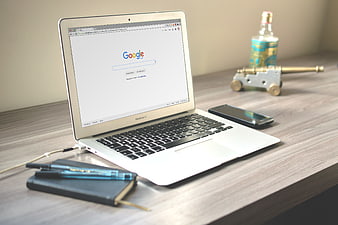 MacBook Air on wooden desk with Google search page