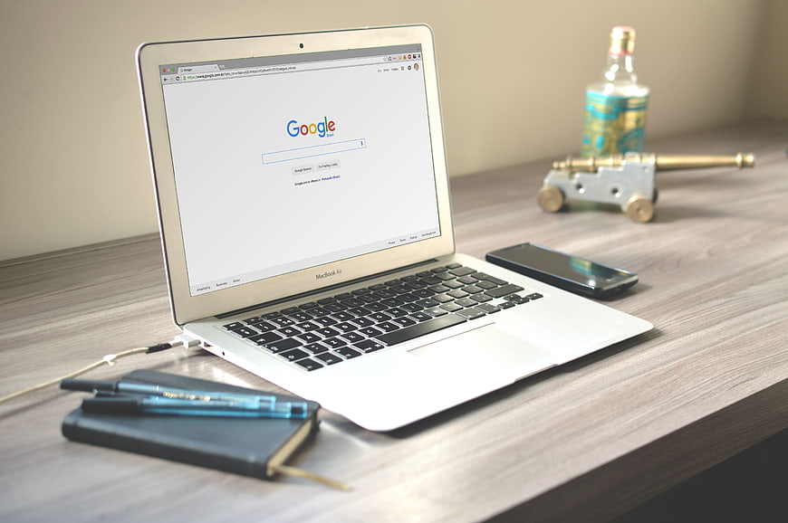 MacBook Air on wooden desk with Google search page