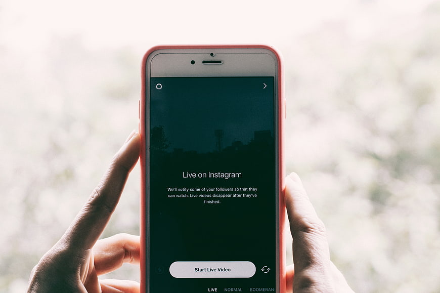 Hands holding smartphone with Instagram Live video interface