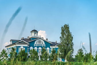 Blue wooden manor house with white trim in summer landscape