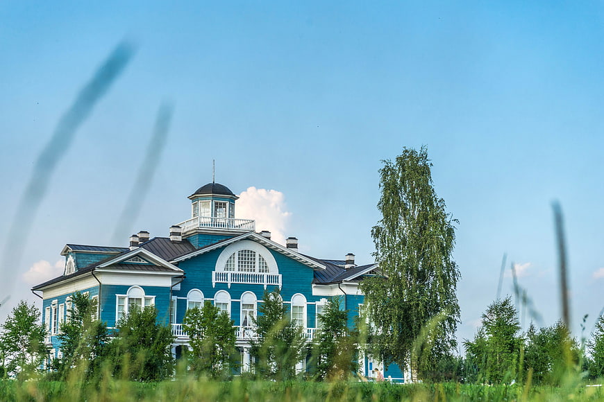 Blue wooden manor house with white trim in summer landscape