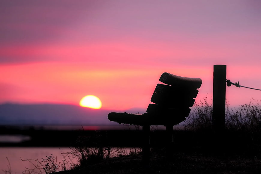 Silhouette of Empty Bench Against Vibrant Pink Sunset
