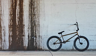Gold BMX Bicycle Leaning Against Weathered Concrete Wall