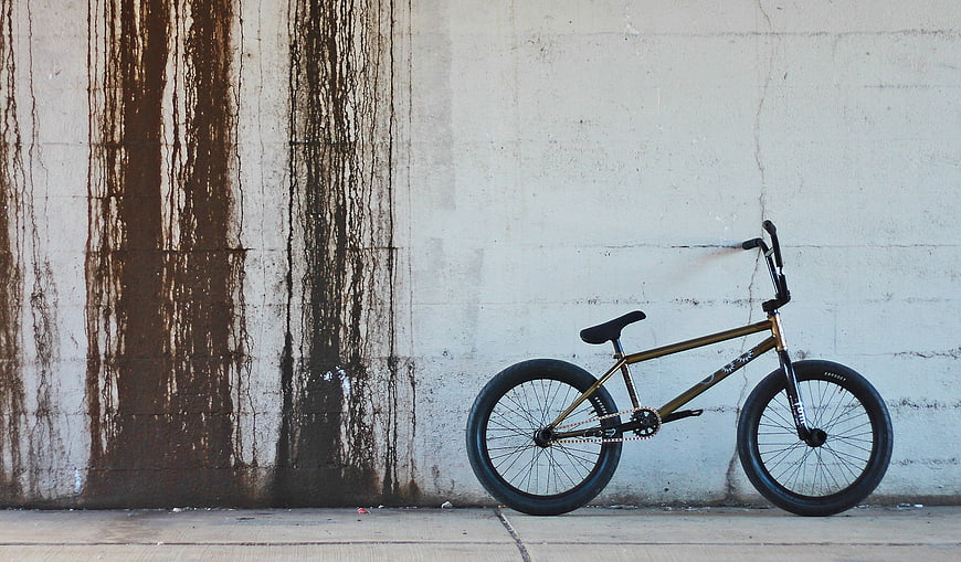Gold BMX Bicycle Leaning Against Weathered Concrete Wall